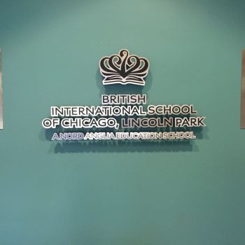 Metal wall sign with layered lettering and logo mounted on teal wall in Chicago Downtown.