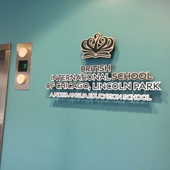 Dimensional metal wall sign with layered lettering and logo mounted on blue wall in Chicago