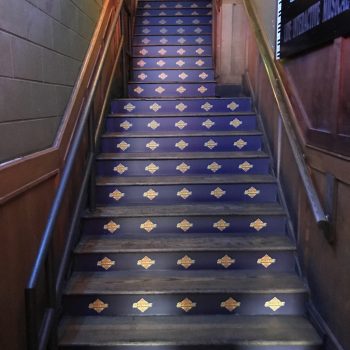 Indoor stair riser graphics with repeated logos on wooden steps in Chicago Downtown.