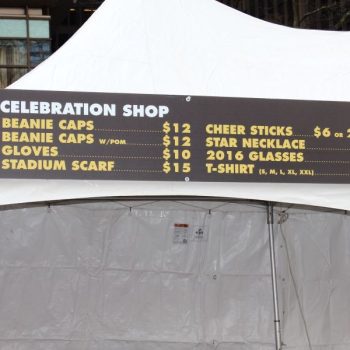Large vinyl banner with event merchandise pricing mounted on a white tent in Chicago Downtown.