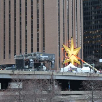 Large yellow star-shaped event sign mounted on building wall with tents in Chicago Downtown.