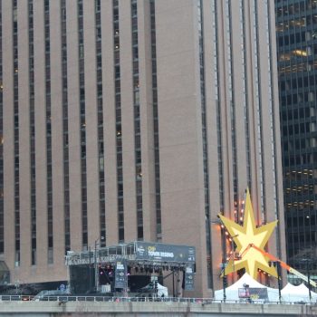 Large yellow star-shaped event sign mounted on a metal frame with tents in Chicago Downtown.