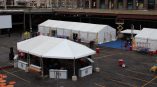 White event tents with printed fabric signs and tables set up in a parking lot in Chicago Downtown.