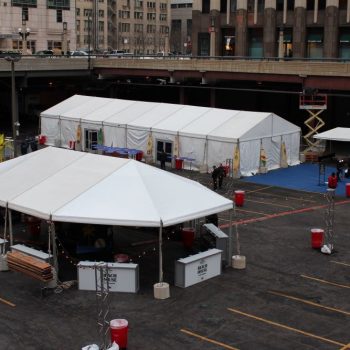 White event tents with printed fabric signs and tables set up in a parking lot in Chicago Downtown.