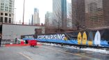 Large outdoor vinyl event banner with surfboard graphics installed on fence in Chicago Downtown.