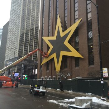 Large yellow star-shaped wall sign mounted on a brick building in Chicago Downtown.