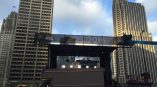 Large vinyl event banner mounted on scaffolding above a stage in Chicago Downtown.