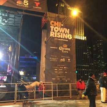 Large vertical event banner on metal frame with logos at night in Chicago Downtown.