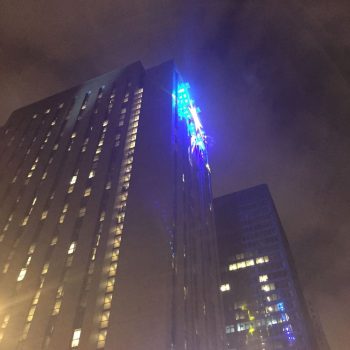 Illuminated building-mounted LED sign with blue lights on a skyscraper in Chicago Downtown.