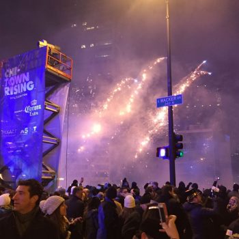 Large vertical event banner on a metal frame at a crowded outdoor celebration in Chicago Downtown.