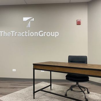 Metal wall sign with cut-out letters and logo mounted above desk in Chicago Downtown office.