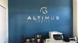 Metal wall sign with raised letters and logo mounted on blue wall in Chicago Downtown office.