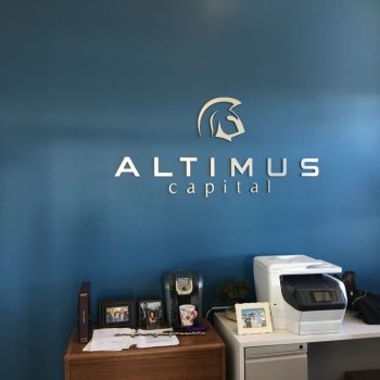 Metal wall sign with raised letters and logo mounted on blue wall in Chicago Downtown office.