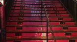 Red vinyl floor graphics applied to wooden stairs with black handrails in Chicago Downtown.