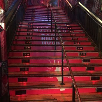 Red vinyl floor graphics applied to wooden stairs with black handrails in Chicago Downtown.