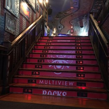 Red vinyl stair graphics with white design and text on wooden stairs in Chicago Downtown.