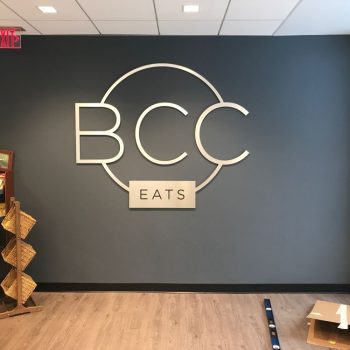 Brushed metal wall sign with circular logo and letters installed in Chicago Downtown.