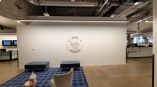 Round wall sign with city skyline graphic mounted on white office wall in Chicago Downtown.
