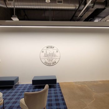 Round wall sign with city skyline graphic mounted on white office wall in Chicago Downtown.