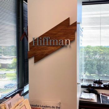 Dimensional metal office wall sign mounted on wooden backer panel in Chicago Downtown.