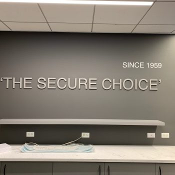 Metal wall sign with raised letters mounted on gray wall above countertop in Chicago Downtown.