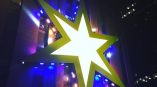 Large illuminated star-shaped wall sign with LED lights on building facade in Chicago Downtown.