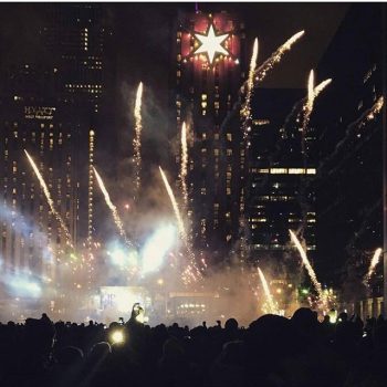 Illuminated star-shaped rooftop sign with fireworks display in Chicago Downtown at night.