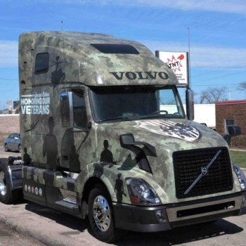 A camo patterned vehicle wrap on the front of a semi truck