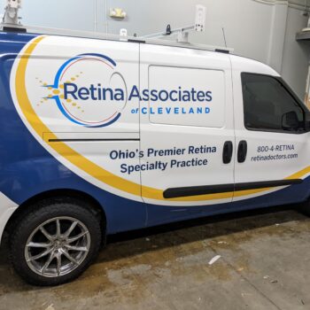 A blue, white, and yellow transit van with a logo and design for retina associates