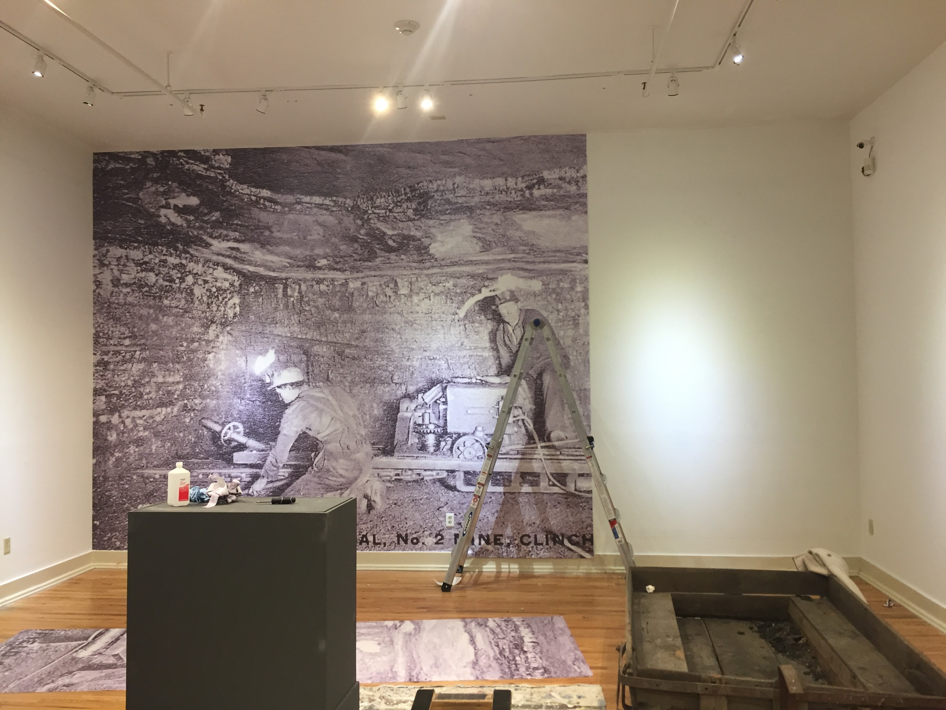 Black and white wall mural of coal workers being installed