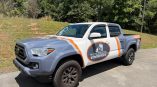 Partial fleet vehicle wrap with gray, white, and orange graphics on a pickup truck in Tri-Cities -
