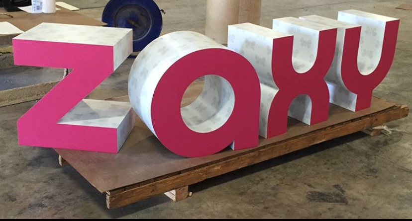 Composite material pink and white letters on wooden pallet display.