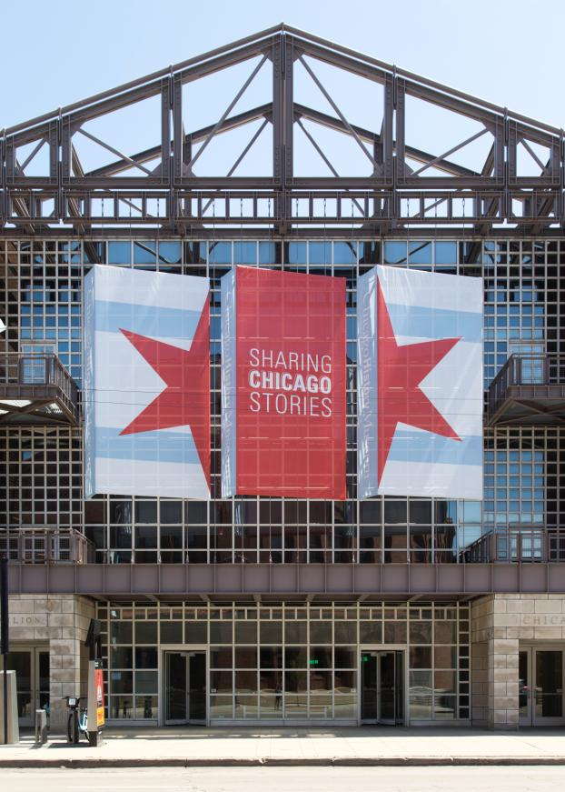 Tall building with large banner displaying Sharing Chicago Stories message