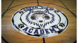 A large print logo made by Speed Pro Imaging at the center court spot of a basketball court.