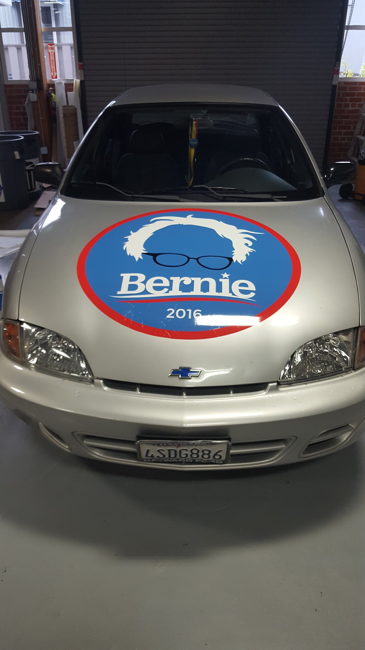 A Bernie Sanders campaign logo on the hood of a small Chevy car.
