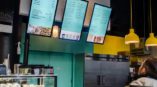 man looking at digital menu boards  on walls of restaurant