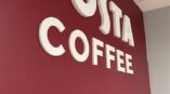 white acrylic Costa logo on red wall