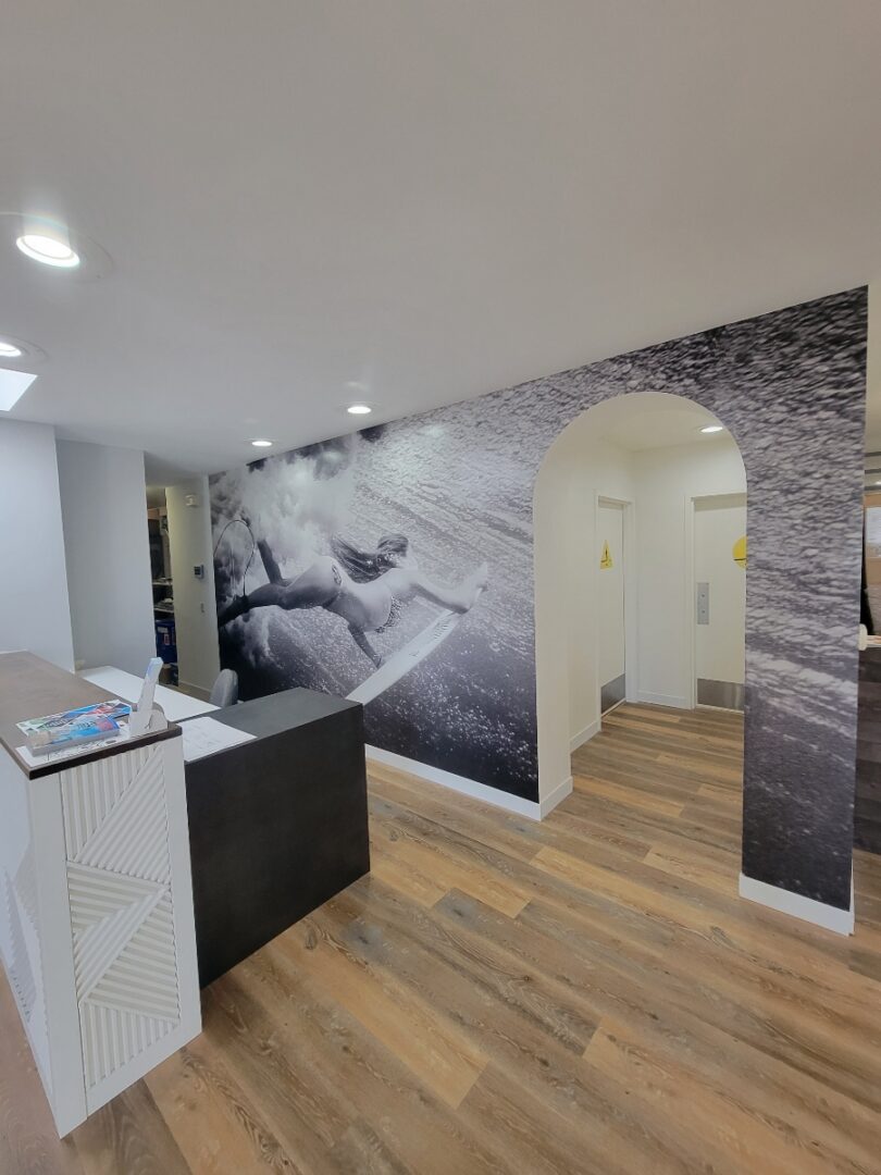 Wall behind check in desk showing grayscale vinyl mural of a surfer