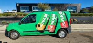 Van with full vehicle wrap of drink cans for Runa in front of building