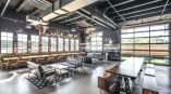 Various dining tables in a food hall with a grayscale vinyl mural in background