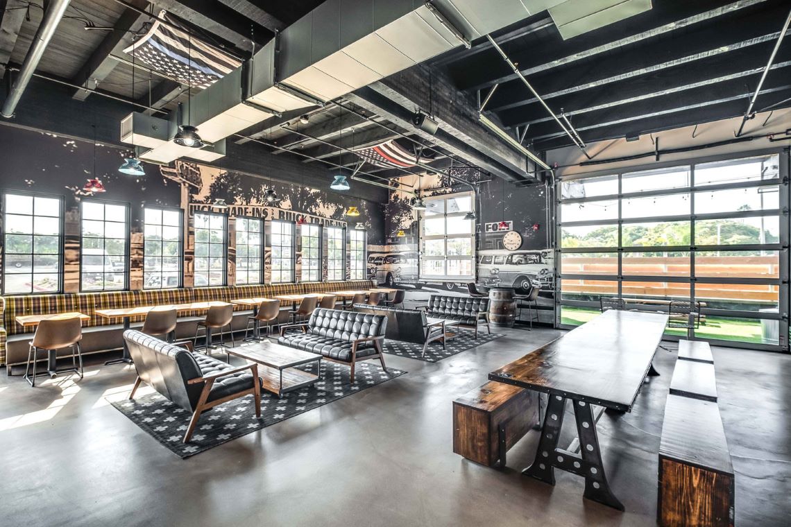 Various dining tables in a food hall with a grayscale vinyl mural in background