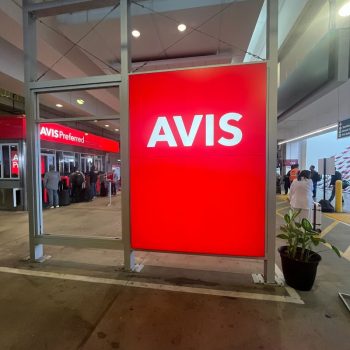 Illuminated red and white backlit storefront sign mounted on metal frame in San Diego, CA.