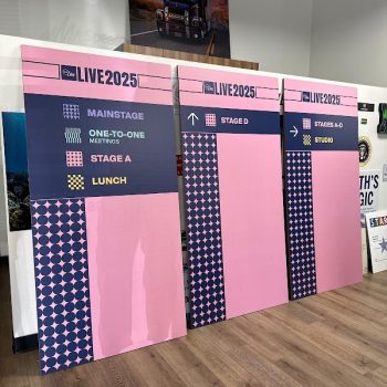 Three large pink and navy wayfinding signs on foam board with event directions in San Diego, CA.