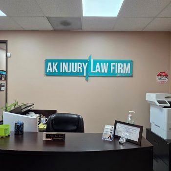 Two-piece acrylic wall sign mounted on beige office wall behind reception desk in San Diego, CA.