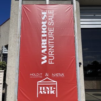 Large red vinyl banner with white text mounted on metal frame outside building in San Diego, CA.