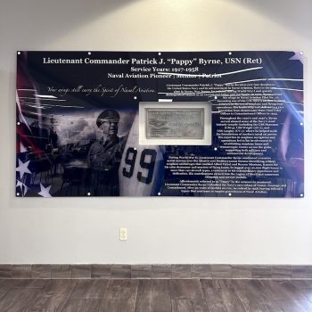 Large acrylic wall sign with military tribute graphics and text mounted on a white wall in San