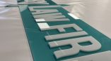 Teal acrylic wall sign with raised white lettering on a table in San Diego, CA.
