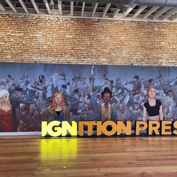 Large printed wall mural with illustrated characters and illuminated 3D letters on wooden floor in