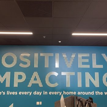 Large wall-mounted lobby sign with striped letters on a blue wall in San Diego, CA.