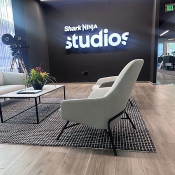 Illuminated white channel letters mounted on a black wall in a modern office lobby in San Diego, CA.